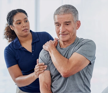 Physical therapist guiding a patient through a shoulder exercise